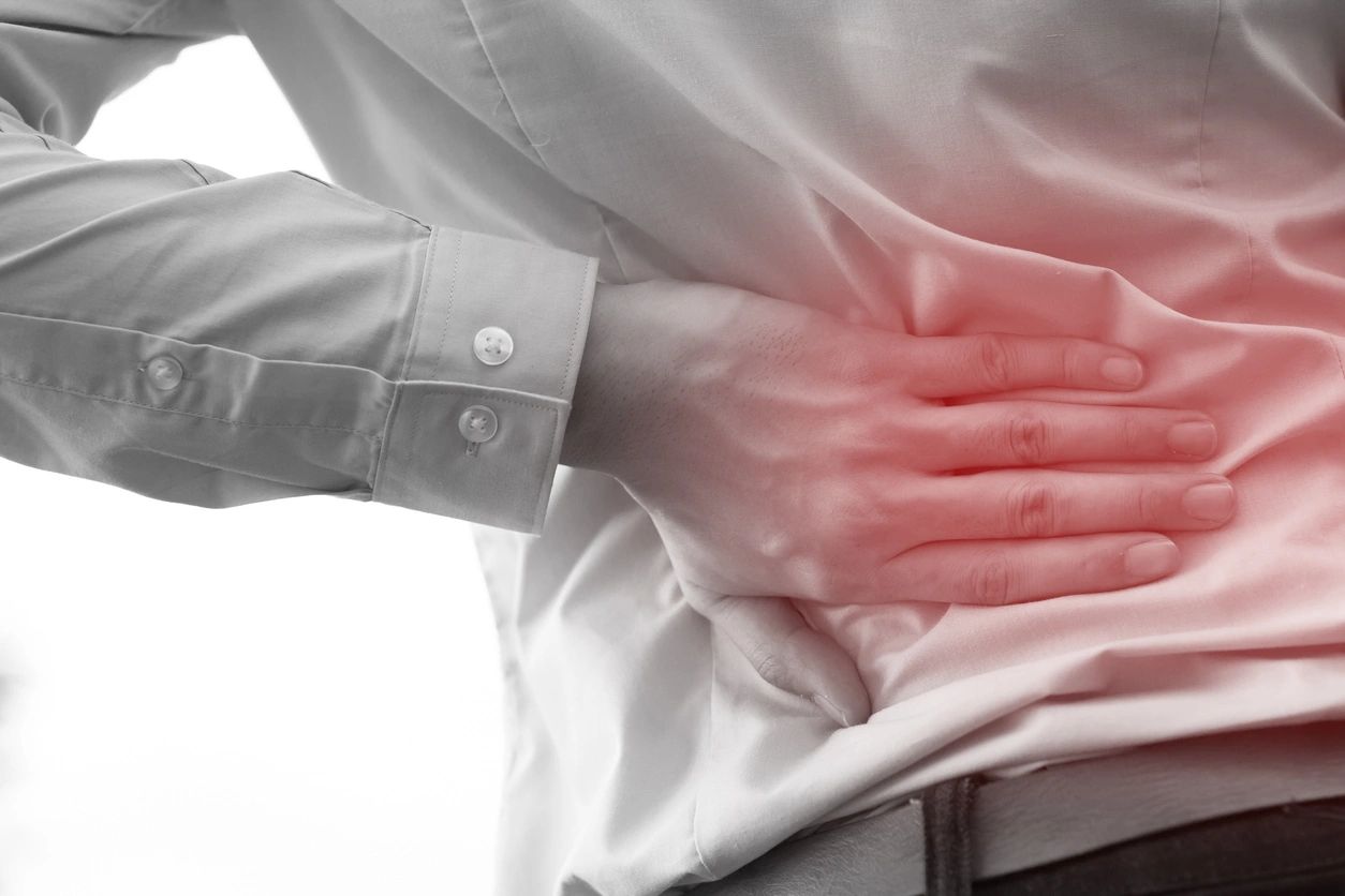 Person holding their lower back indicating chronic back pain