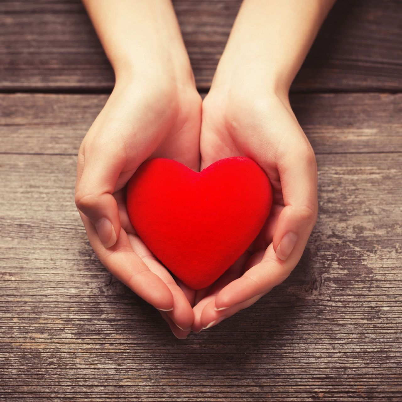 Two hands gently cradling a glowing heart — symbolising healing and care