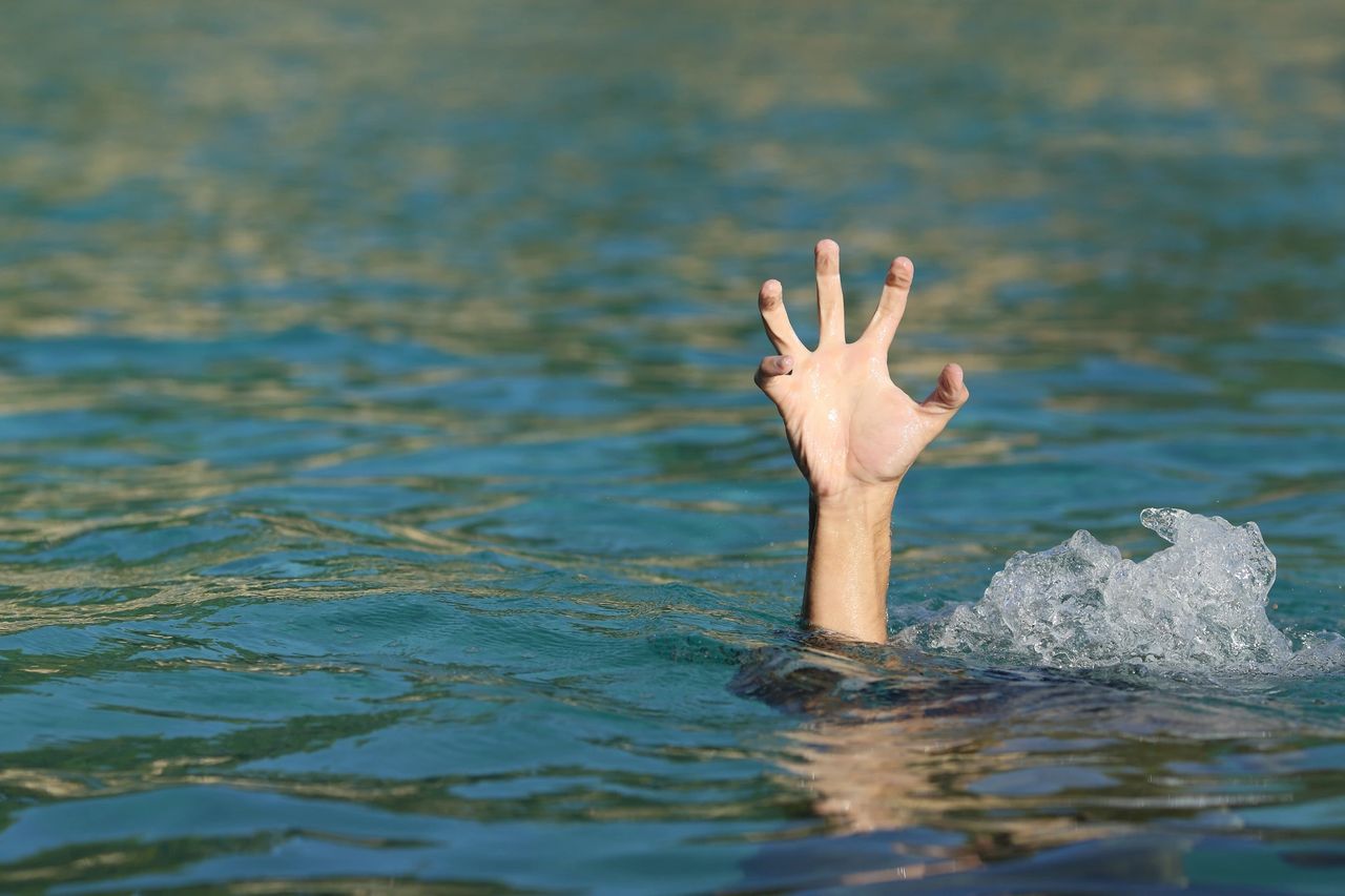 A hand reaching upward from ocean water — reaching for more than good enough